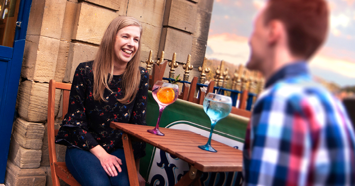 man and woman smiling whilst drinking cocktails